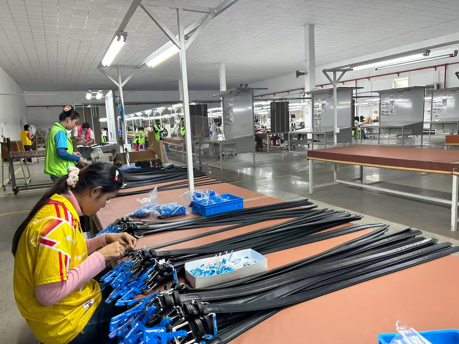 operators working along a belt assembly line where straps and buckles are joined into finished belts