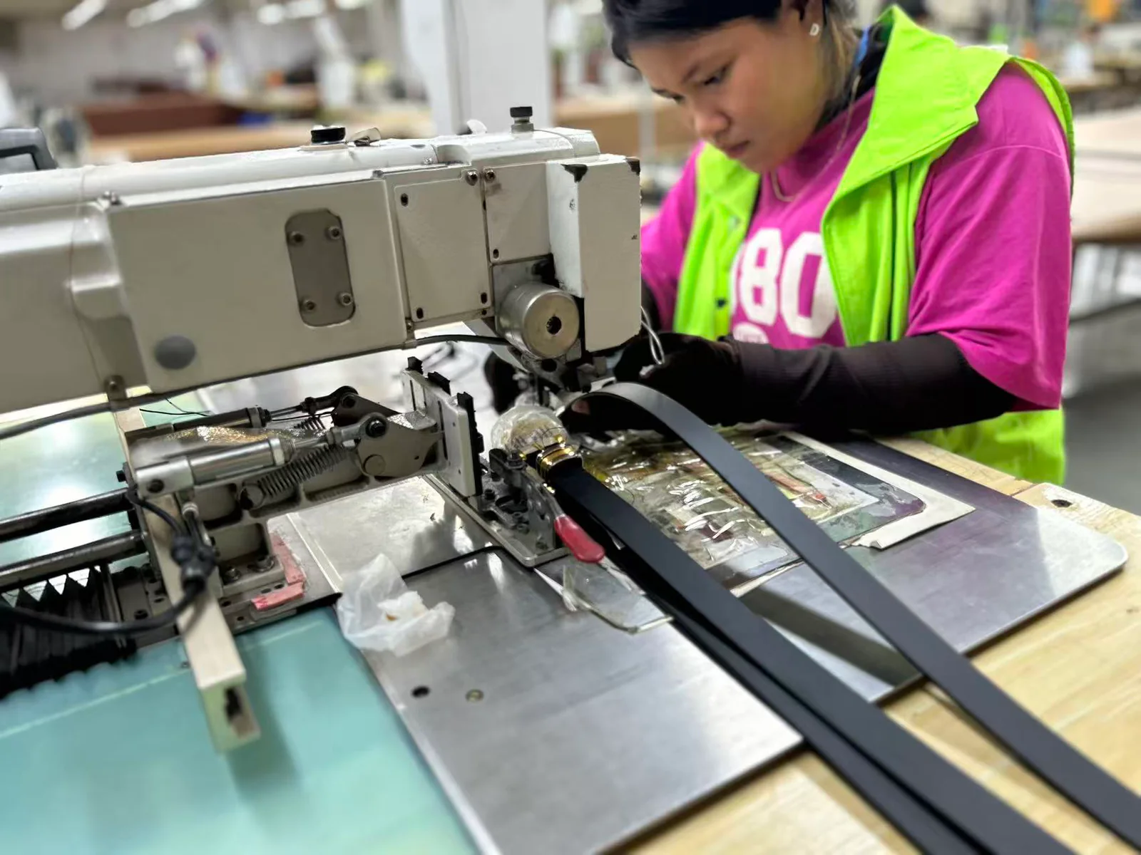 worker sewing black belt straps on an industrial machine