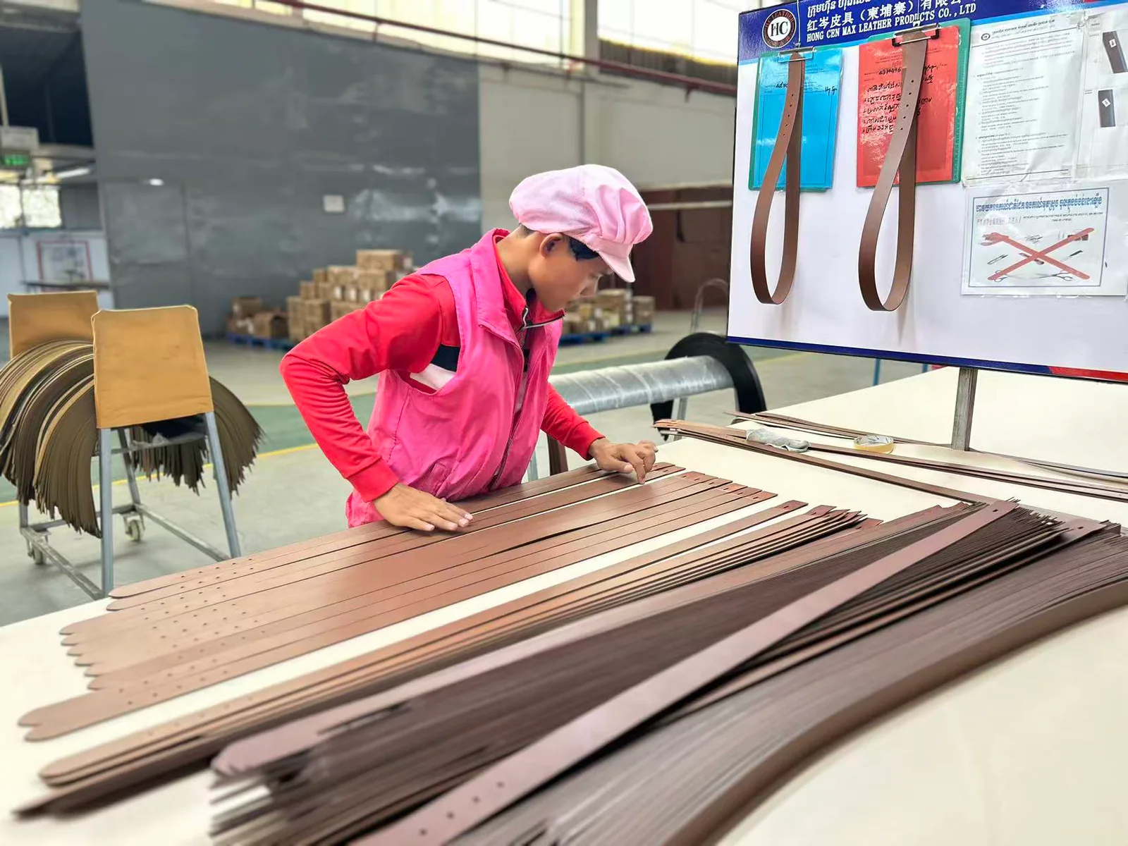 Brown belt straps stacked at a HongDing factory workstation