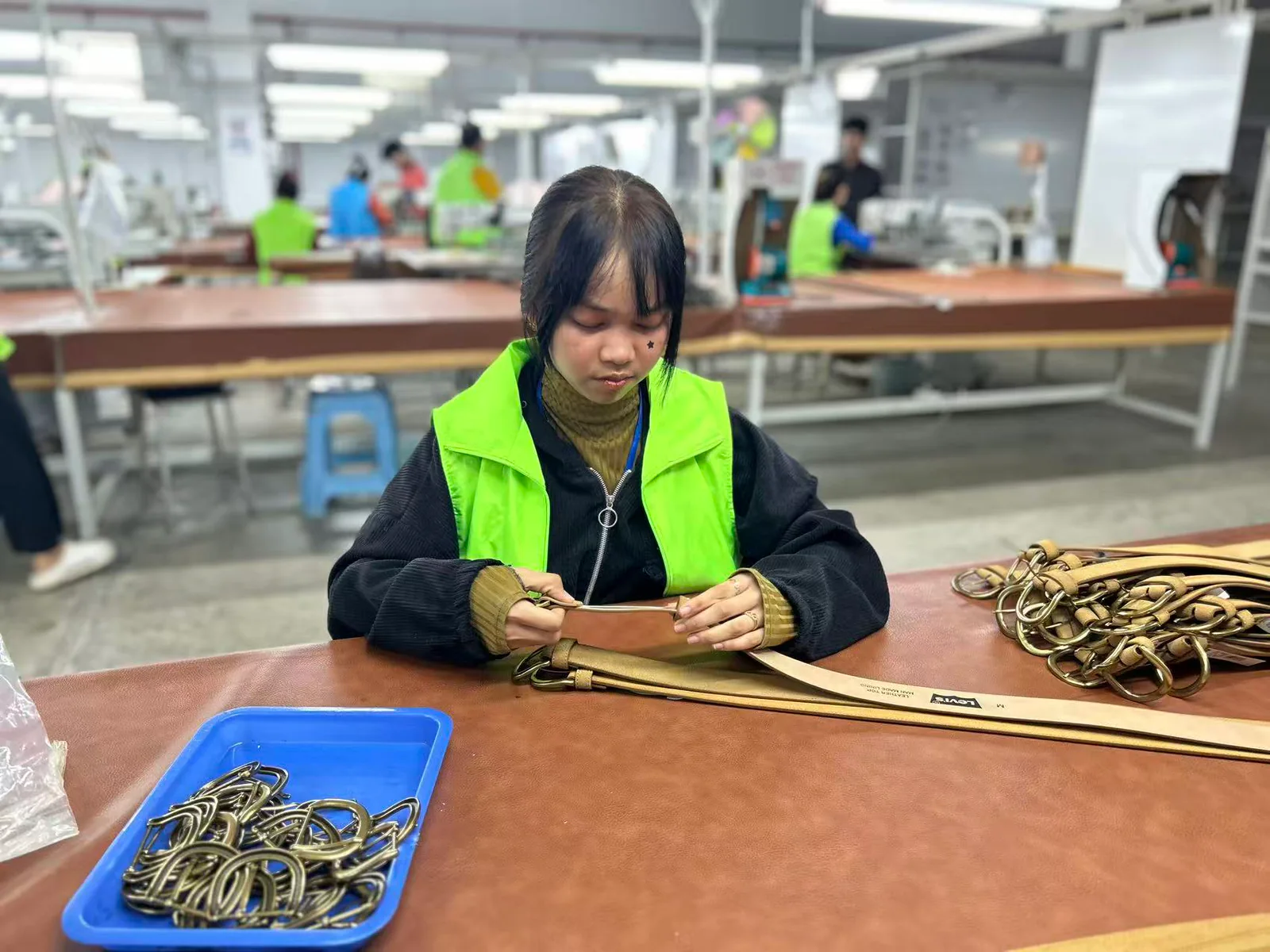 worker assembling buckles at a belt production station