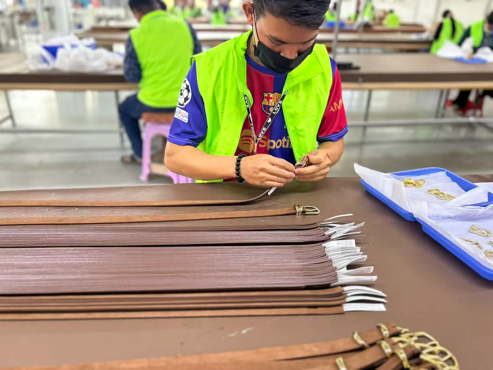 Worker fitting frame buckles to prepared brown belt straps