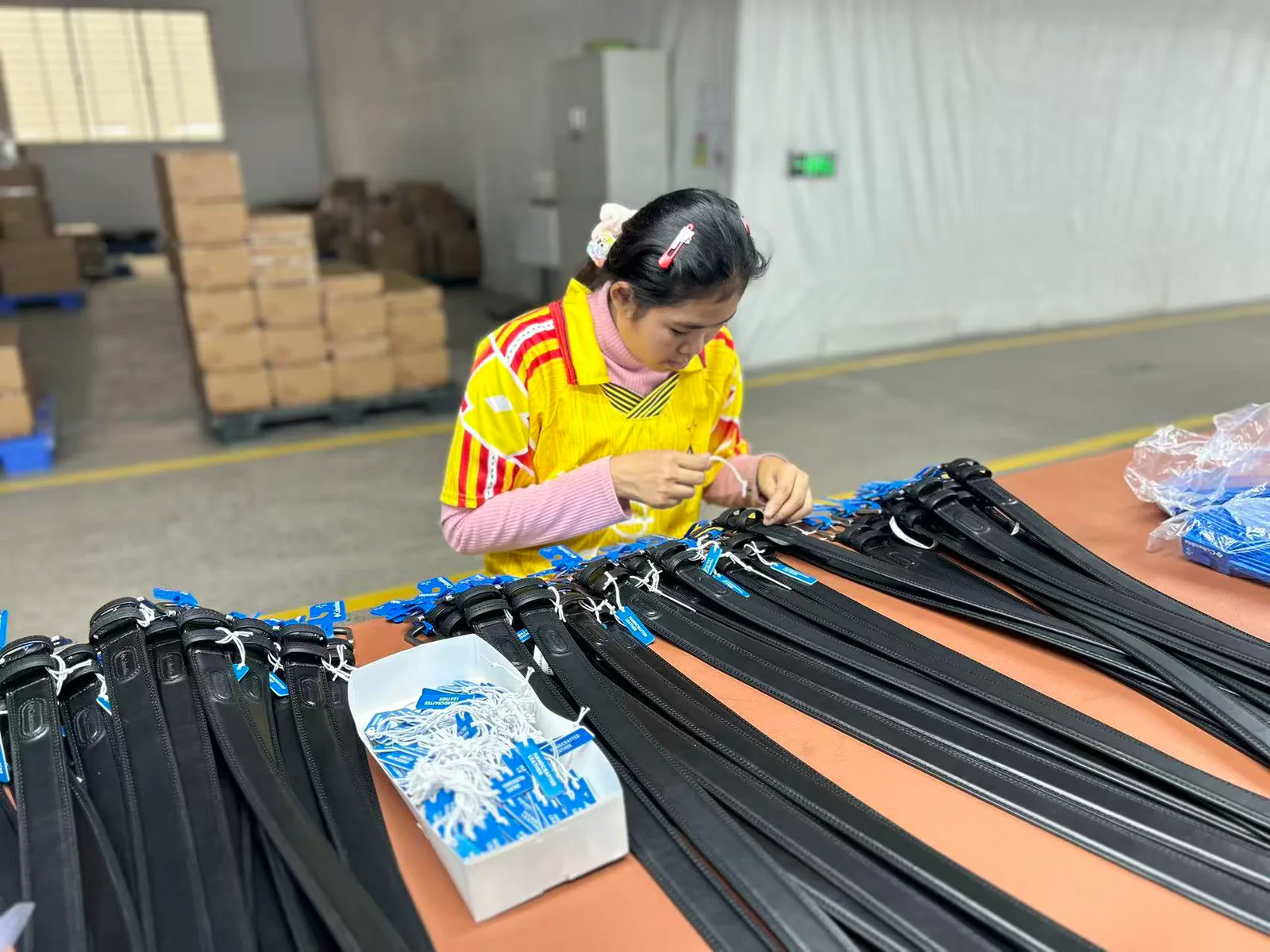 worker attaching labels to finished black belts