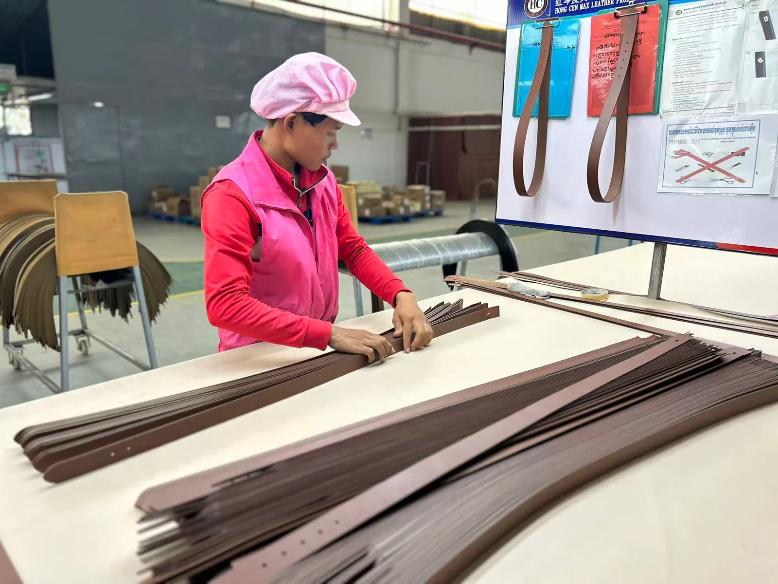 worker sorting prepared brown belt straps at a factory workstation