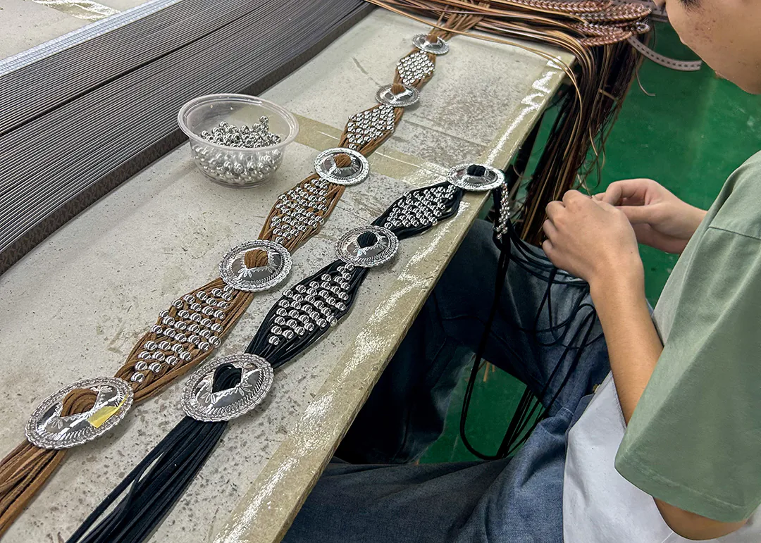Worker assembling conchos and decorative hardware on western belts