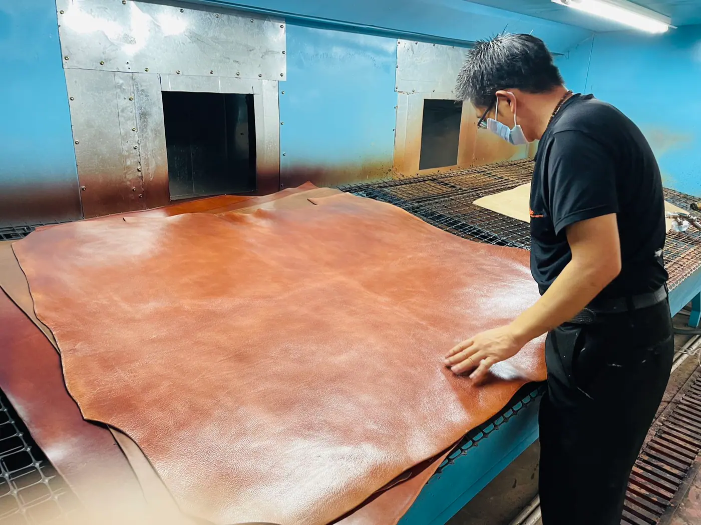worker inspecting the surface of a leather hide at a finishing facility