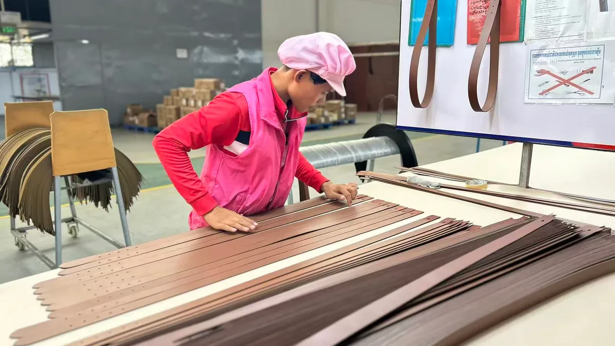 Worker stacking accepted brown belt straps at a workstation