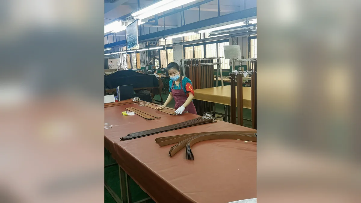 Worker hand-cutting long brown leather belt straps