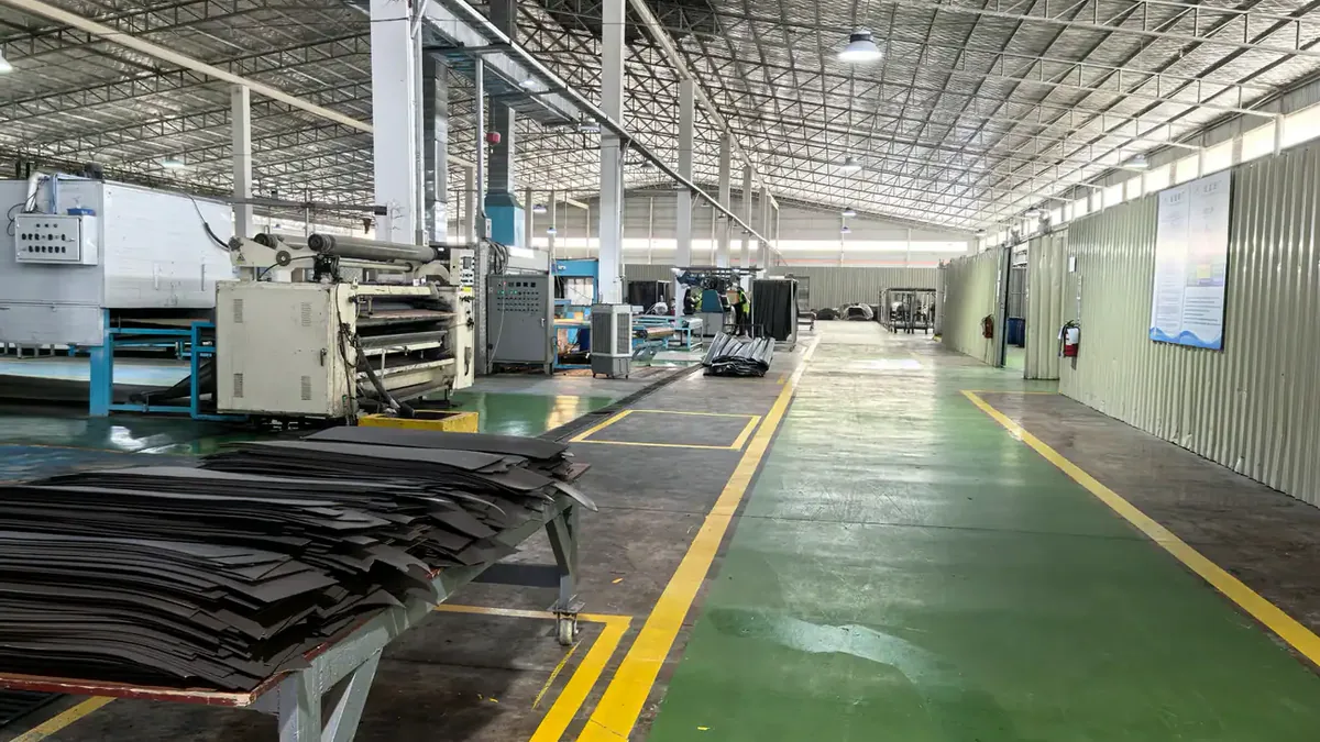 Dark leather hides staged beside processing machinery